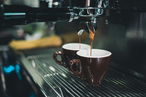 A woman enjoying a cup of coffee while staying hydrated with water, balancing caffeine intake for overall well-being.