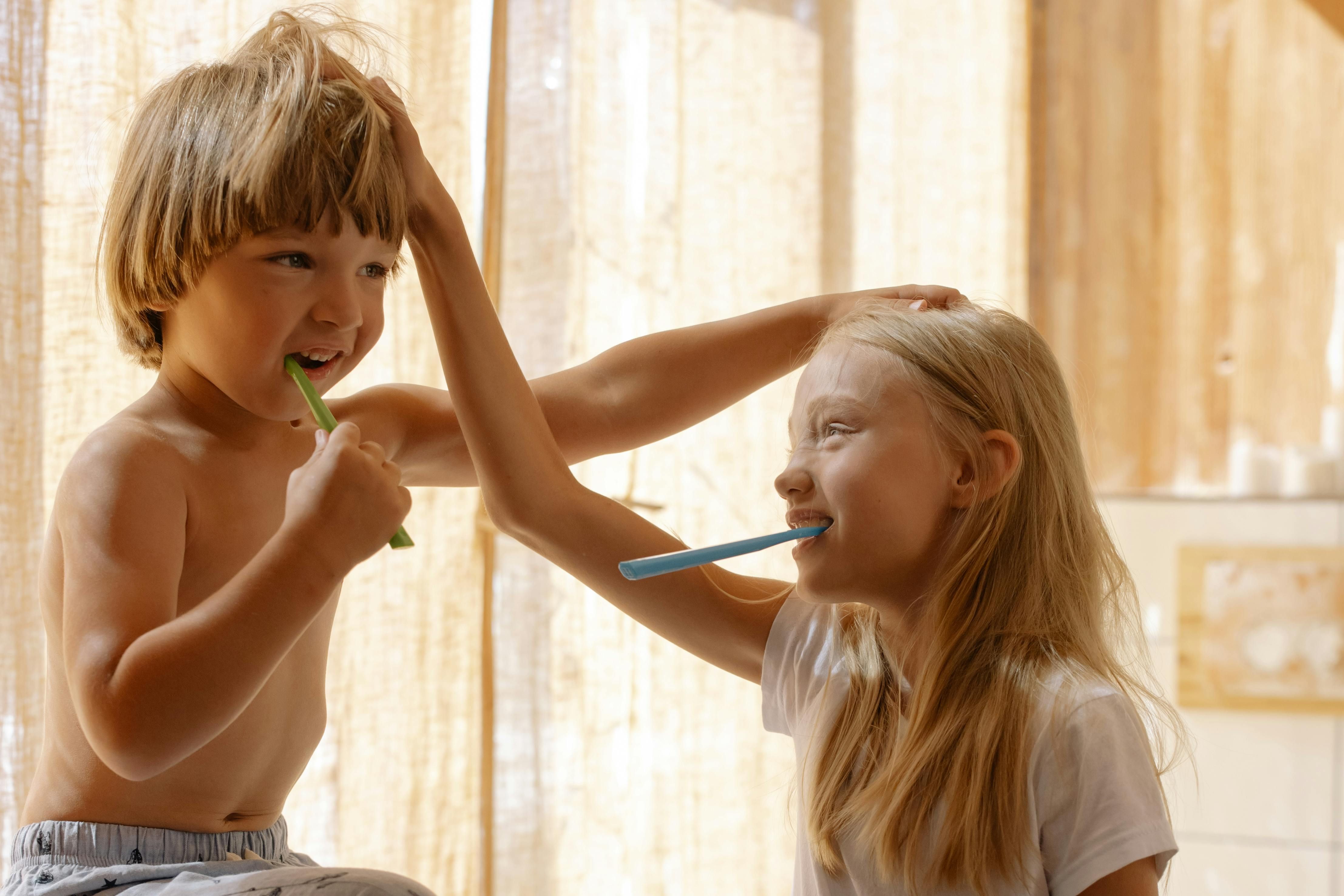 Young children brushing teeth, demonstrating proper oral hygiene technique