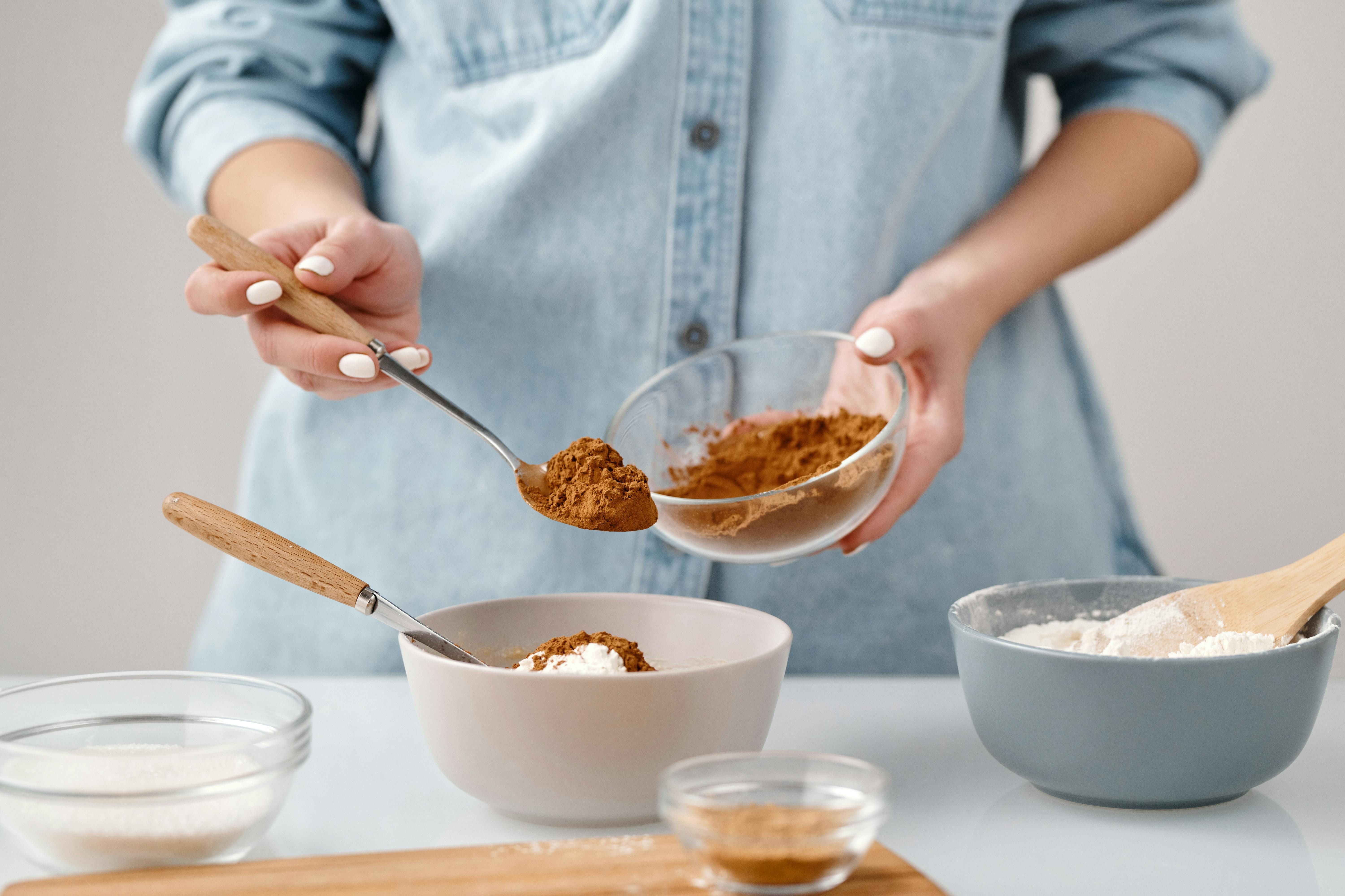 Woman sprinkling cinnamon into a dish while cooking, enhancing flavor naturally.