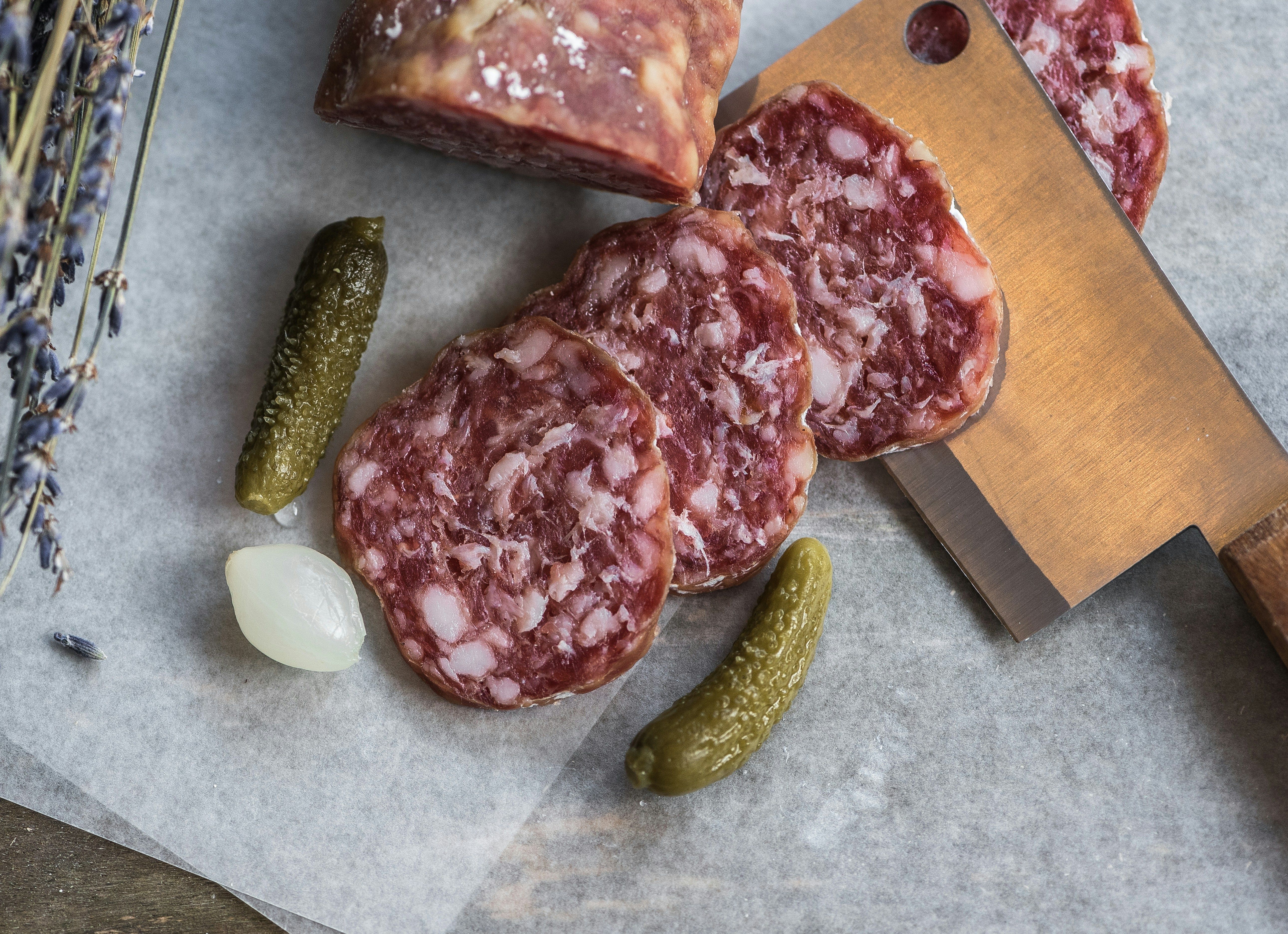 Various types of meat on a table with pickled cucumbers