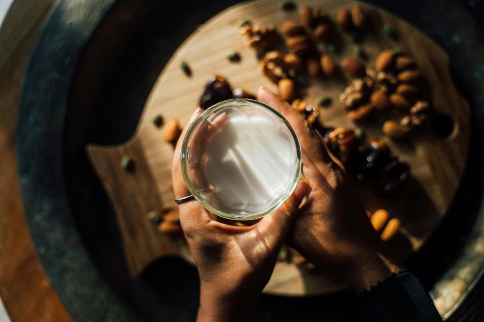 A woman pouring almond milk into a glass, choosing a plant-based option for hydration and wellness.