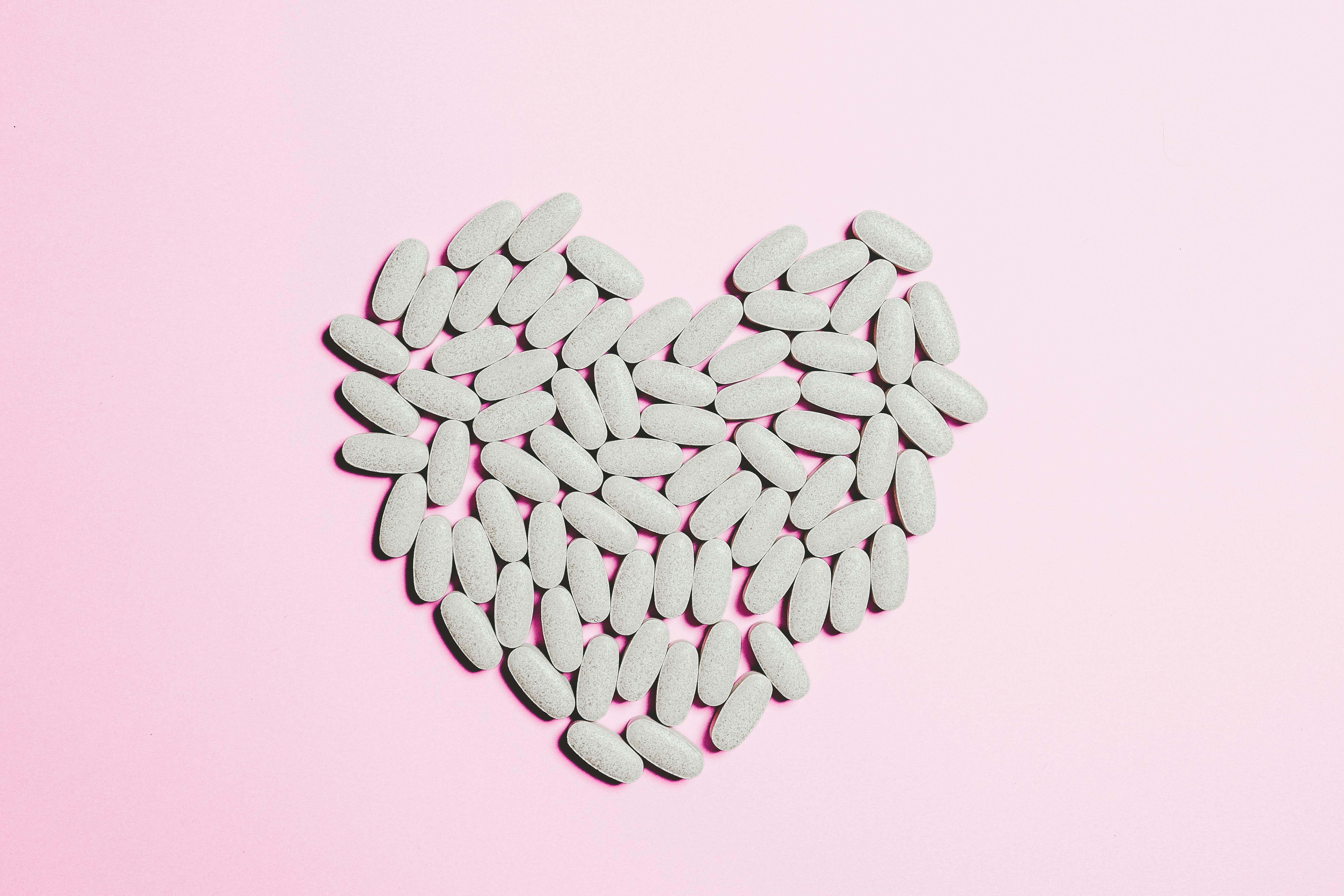 Woman creating a heart shape with supplement pills for women's health