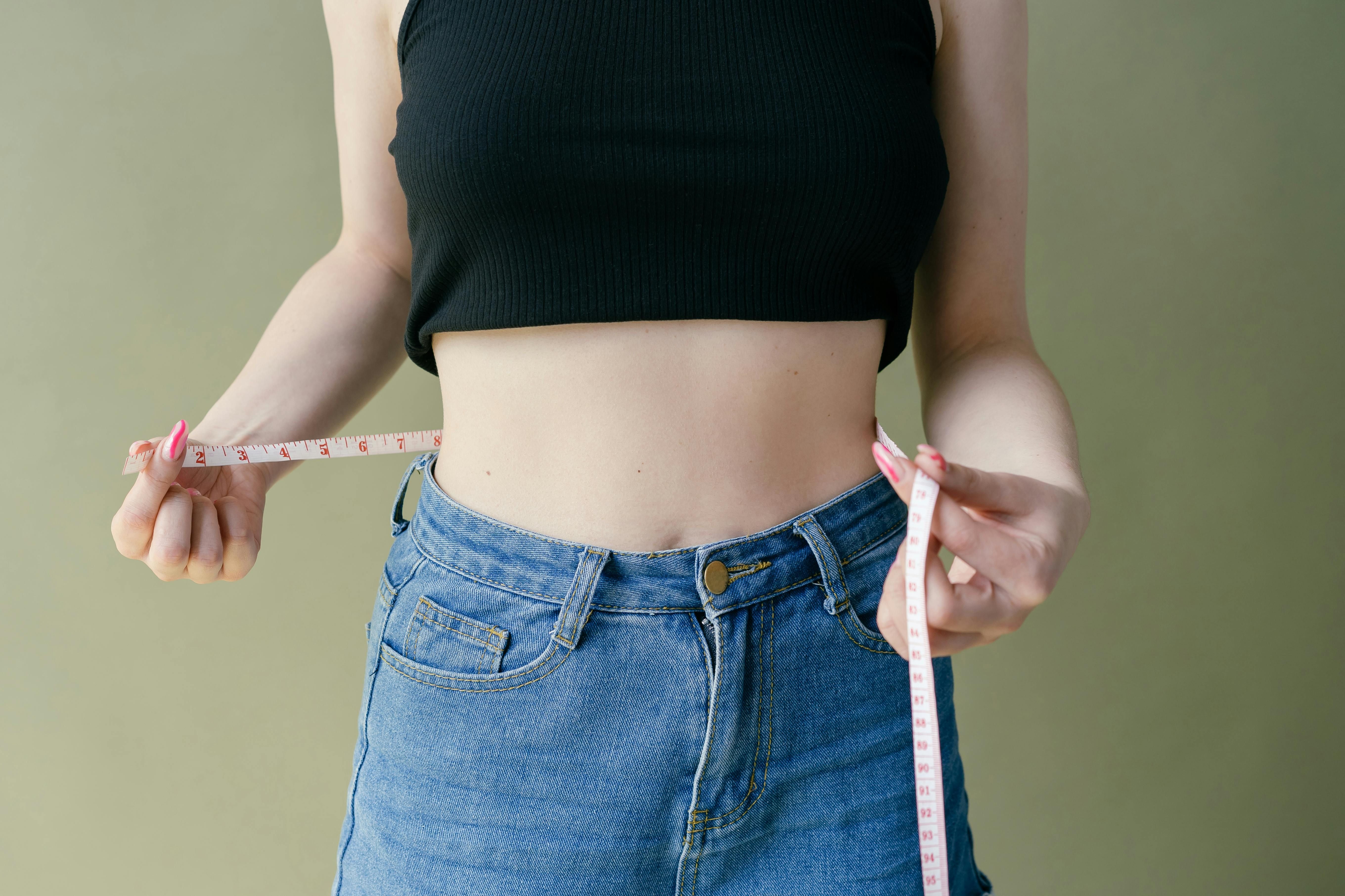 Woman measuring her waistline, highlighting the link between weight loss and sleep apnea improvement