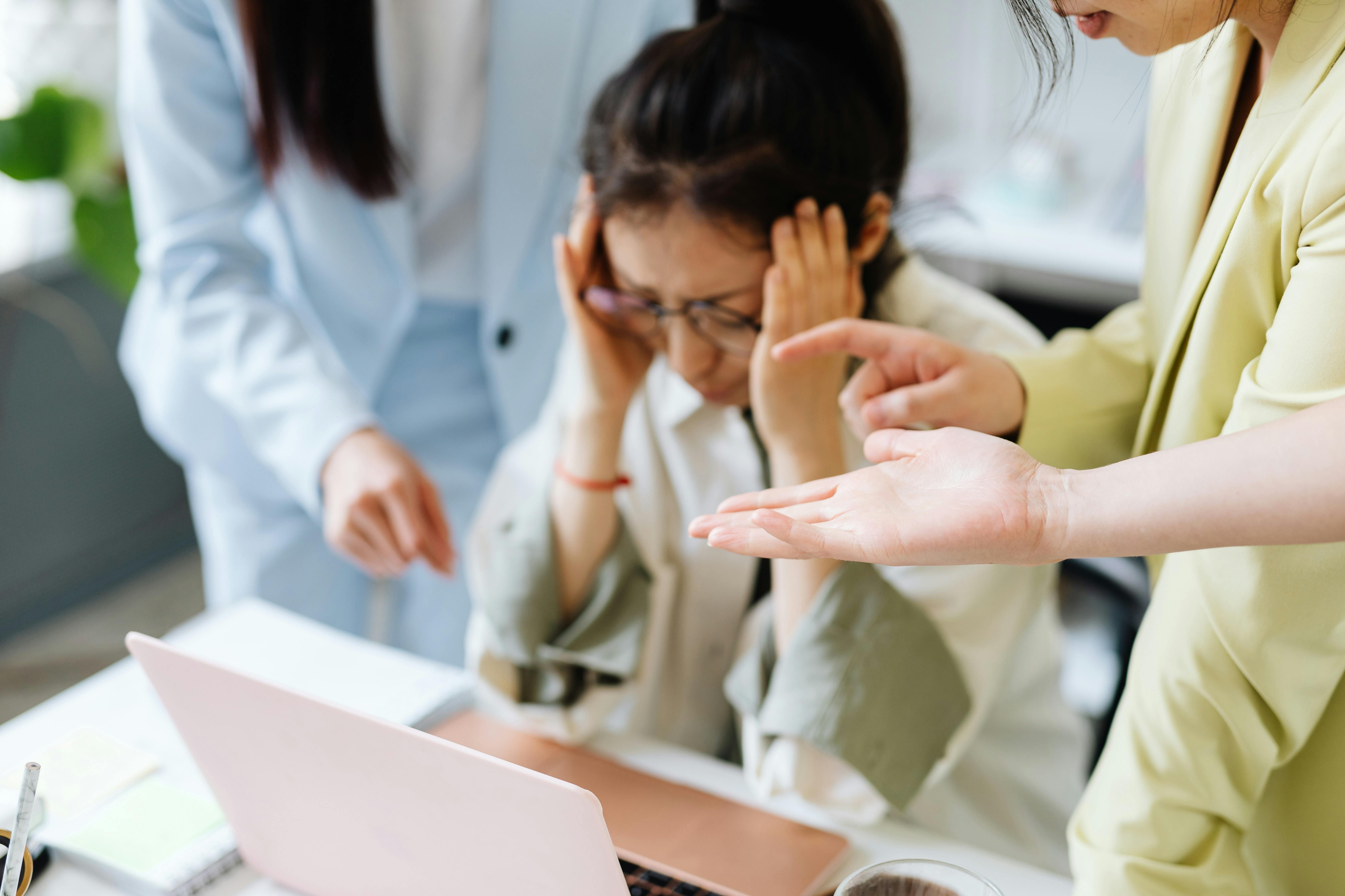 A woman sitting on a chair, holding her head in pain from a migraine.