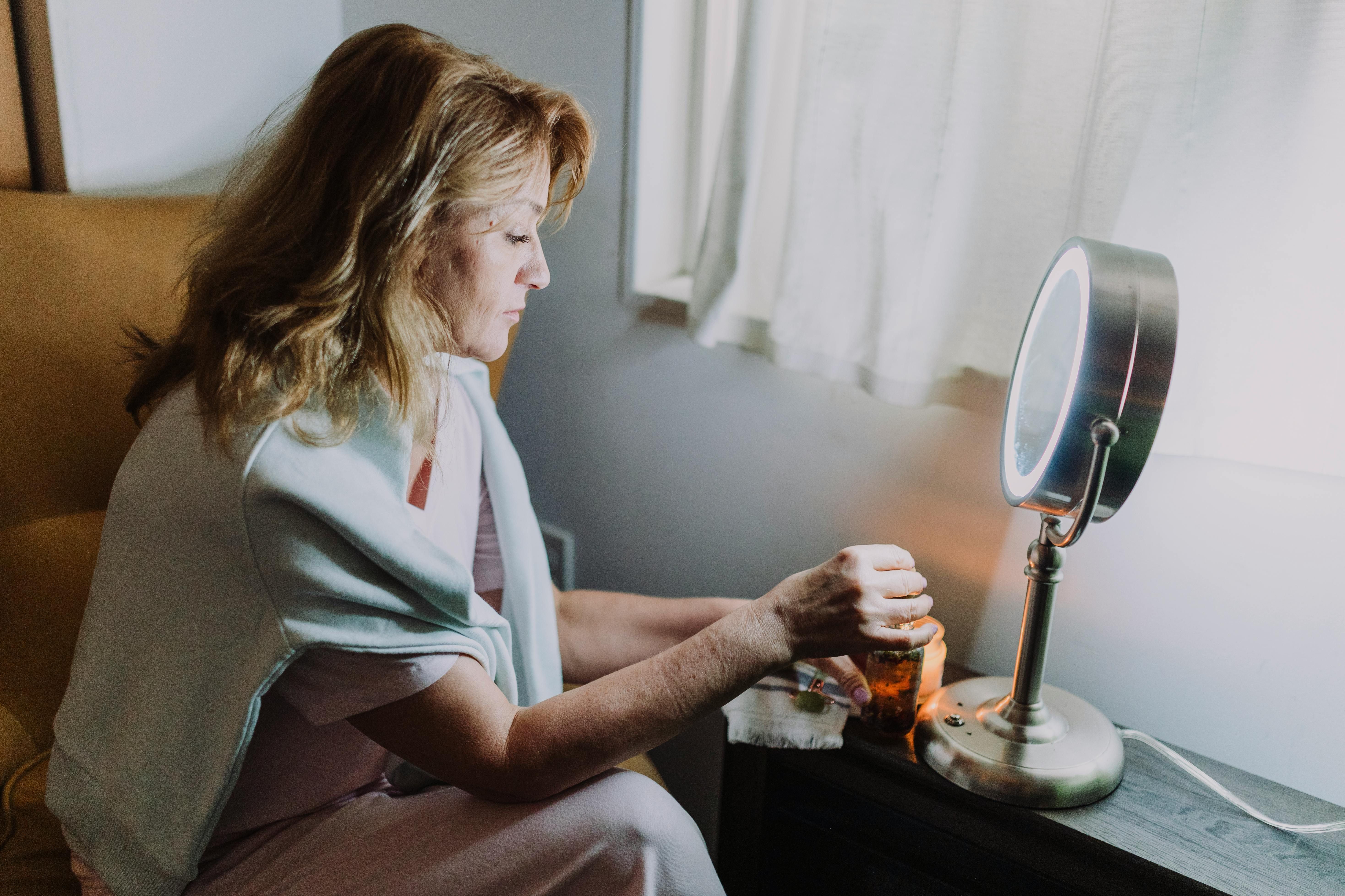 An older woman applying a serum as part of her nighttime beauty routine to hydrate and rejuvenate her skin for a youthful glow.