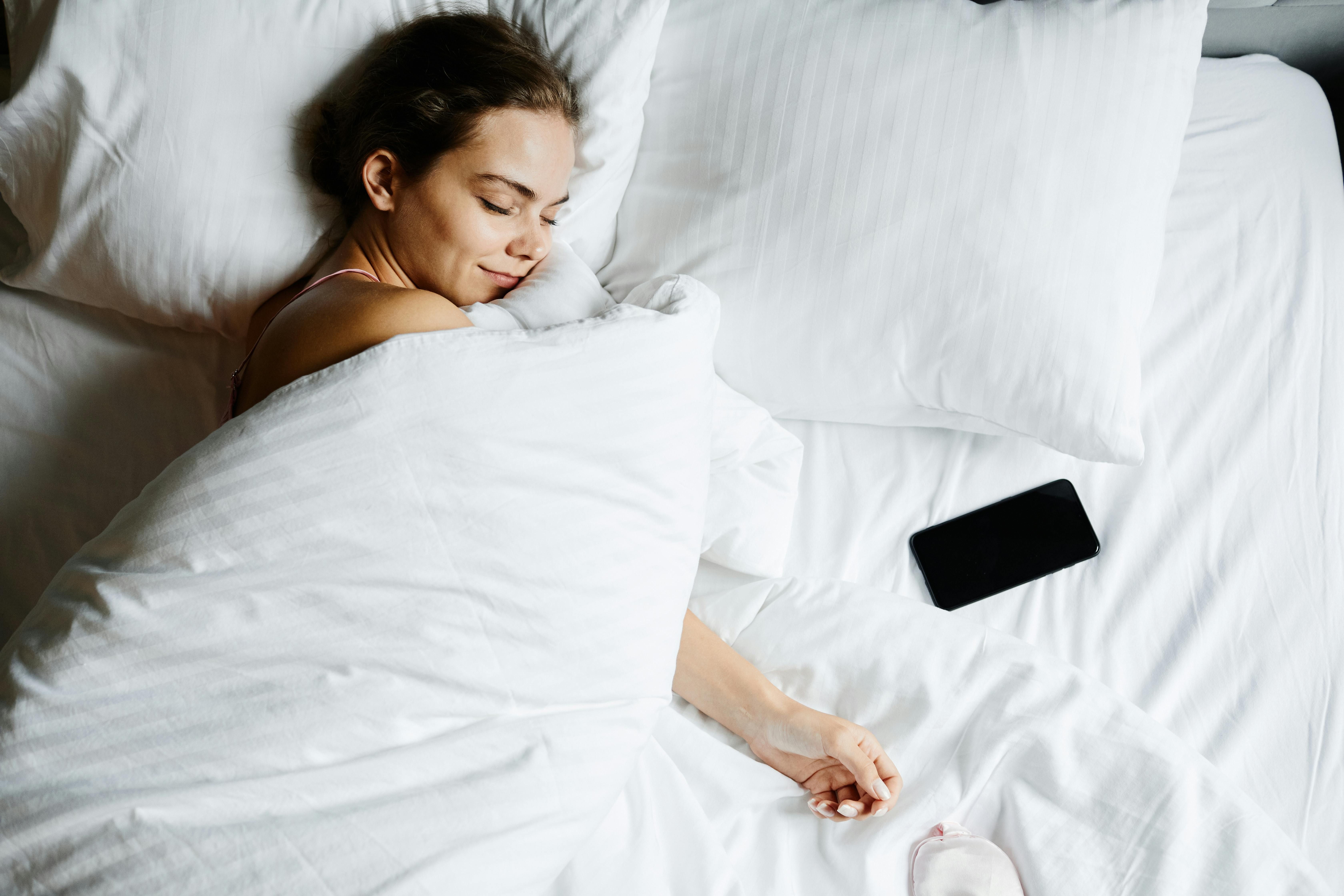 A woman sleeping peacefully in a hotel bed, prioritizing rest to support her weight loss goals while on a business trip.